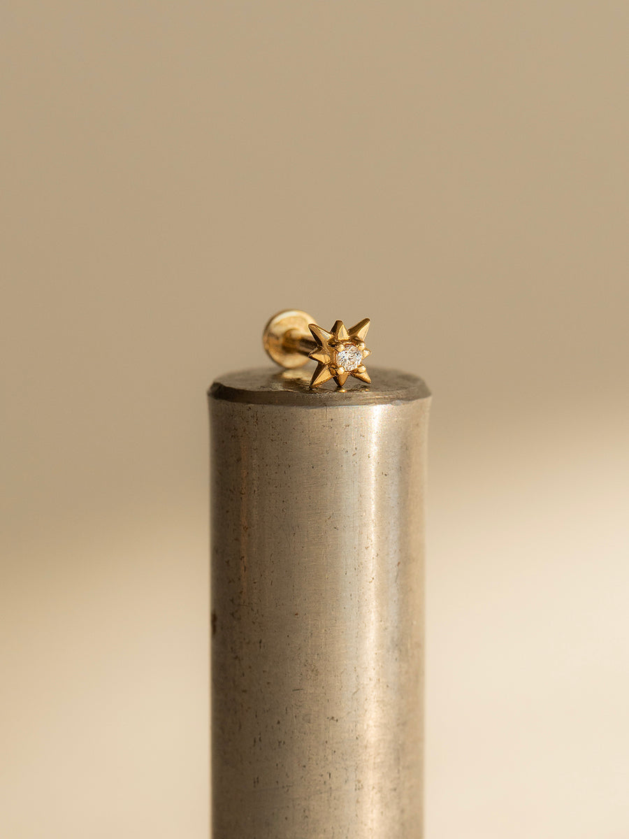 Piercing Grae de oro sólido amarillo de 14k hecho a mano, con diseño de estrella de 5 mm y mecanismo de rosca interna sobre fondo blanco.
