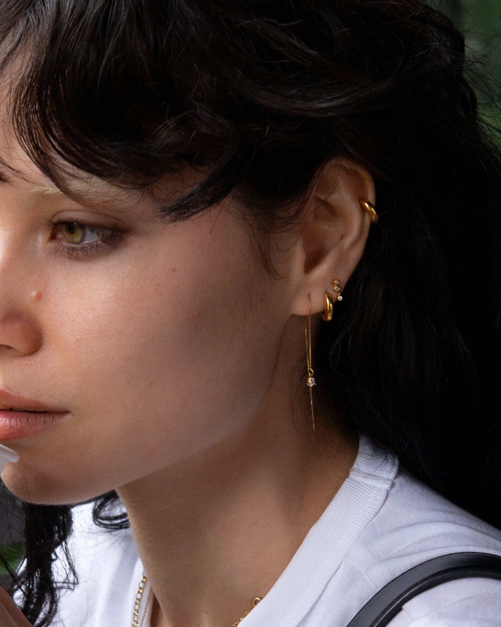 Modelo luciendo el Set Magda enchapado en oro, mostrando la combinación de argollas pequeñas, piercing de circones y aros largos de cadena.