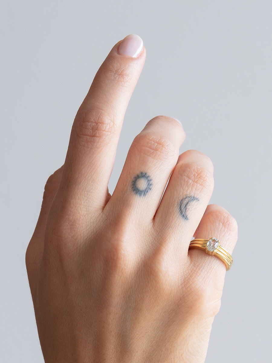 Anillo Inti de bronce macizo hecho a mano con un topacio blanco natural de corte oval sobre una banda con relieve, lucido en la mano de una modelo.