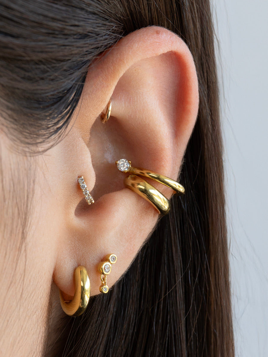 Imagen de referencia del Set Bold enchapado en oro puesto en la oreja, combinando el ear cuff y las argollas para un look moderno.