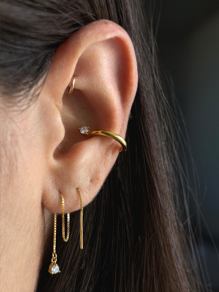 Modelo usando el Set Hannah enchapado en oro, mostrando el ear cuff en el cartílago y el diseño de los aros largos de cadena con circones puestos en la oreja.